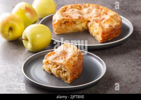 Apfelkuchen mit Käsekruste in der Platte auf dem Tisch zu verschliessen. Horizontal Stockfoto