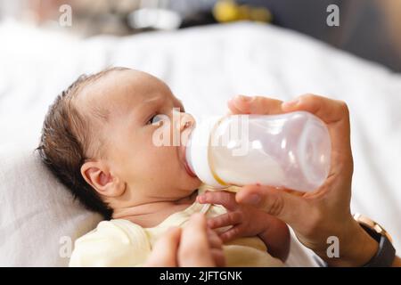 Niedliches neugeborenes Baby, das Milch trinkt, gefüttert von kaukasischer Mutter mit mittlerem Erwachsenen aus der Flasche zu Hause, Platz kopieren. Unverändert, Familie, Liebe, Zweisamkeit, Fürsorge, Innoce Stockfoto