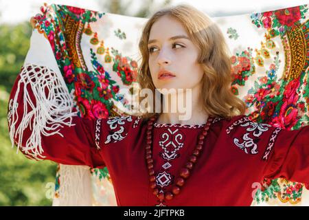 Porträt einer ernsthaften Blondine in traditioneller nationaler Kleidung, die mit einem Schal auf dem Kopf posiert. Stockfoto