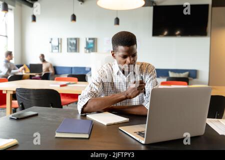 Seriöse junge afroamerikanische Geschäftsmann, der im kreativen Büro am Laptop arbeitet Stockfoto