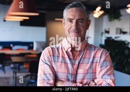 Porträt eines selbstbewussten, reifen kaukasischen Geschäftsmannes im kreativen Büro Stockfoto