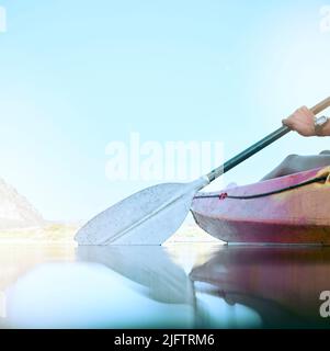 Nahaufnahme des Kajakruders, das auf ruhigem Wasser rudert. Weibliche Hände Kajakfahren auf einem See während der Sommerferien. Frau draußen in der Natur genießt Wasseraktivität Stockfoto