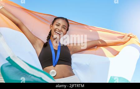 Porträt einer jungen, fit indischen Athletin, die nach dem Sport jubelt und die indische Flagge hält. Lächelnd fit aktiv sportlich Frau Gefühl Stockfoto