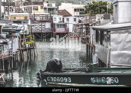 Blechhäuser auf Stelzen am Ufer eines Flusses. Schnellboot im Vordergrund. Stockfoto