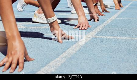 Nahaufnahme einer bestimmten Gruppe von Athleten in der Startposition Linie, um Sprint oder Rennen auf der Sportbahn Stadion zu beginnen. Hände von verschiedenen Sportlern Stockfoto