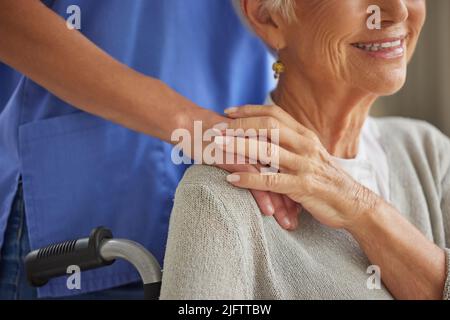 Nahaufnahme eines Arztes, der einen Patienten tröstet und unterstützt, indem er die Hände hält. Gesundheitsfachkraft, die einem älteren Patienten gegenüber gütig ist. Liebevoll Stockfoto