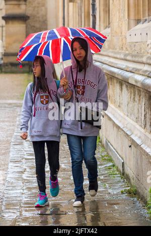 Touristen, die im August an einem regnerischen Tag in Oxford, Oxfordshire, Großbritannien, unter dem Regenschirm von Union Jack bei strömendem Regen Schutz finden Stockfoto