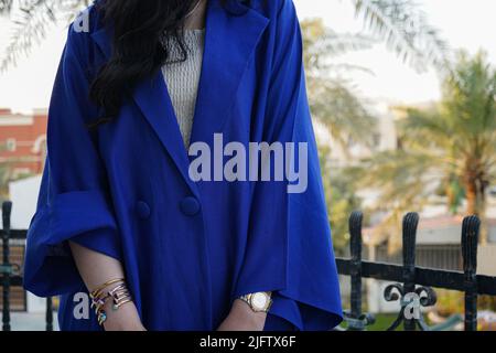 Frau trägt einen modernen blauen Abaya mit einem weißen Oberteil. Blaues Kleid oder Blazer. Stockfoto