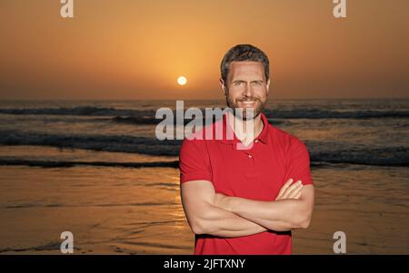 Fröhlicher Mann über dem Meer am Sonnenuntergang Sommerstrand, Platz kopieren, Urlaub Stockfoto