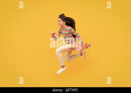 Glücklich energetische Kind Skateboarder springen mit Penny Board Skateboard, Kindheit Stockfoto