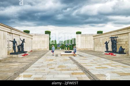 Besucher sehen sich Skulpturen von Ian Rank-Broadley im Zentrum des Armed Forces Memorial im National Memorial Arboretum, Staffordshire, England, Großbritannien, an Stockfoto