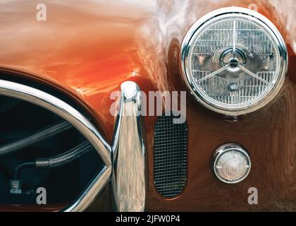Die Frontscheinwerfer und die Grillpartie eines roten AC Cobra klassischen Sportwagens Stockfoto