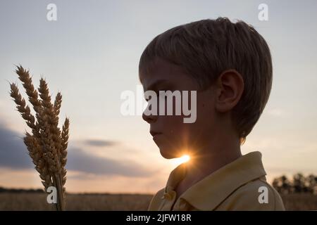 Silhouette des Gesichts eines Kindes und ein Bouquet von Dornen vor dem Hintergrund der untergehenden Sonne. Wunderschöne Sonnenstrahlen. Earth Day Konzept, Öko-Bildung. Die V Stockfoto