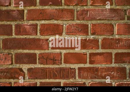 Nahaufnahme einer alten roten Backsteinmauer mit Schnitzereien und Copyspace. Zoomen Sie auf unterschiedliche Größe, Form und Muster von Ziegeln. Details der gebauten Struktur mit Stockfoto