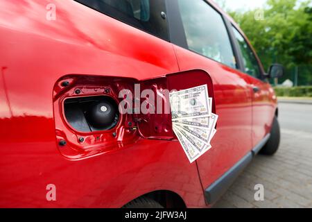 50-Dollar-Scheine, die aus einer offenen Gaskappe auf einem Auto ragen, ein Symbol für steigende Kraftstoffpreise. Stockfoto
