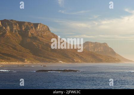 Landschaft, Meer, Strand und Bergblick auf die Twelve Apostles in Kapstadt, Südafrika. Beruhigen Sie das Meer mit blauem Himmel und kopieren Sie die Raumwäsche auf die Ufer Stockfoto