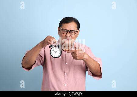 Der Erwachsene asiatische Mann mit rosa Hemd auf dem blauen Hintergrund stehen. Stockfoto