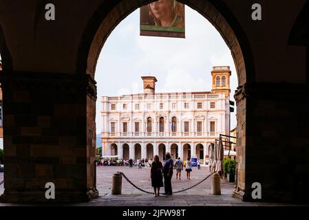 Die Biblioteca civica Angelo Mai durch die Bögen des Erdgeschosses des Palazzo della Ragione gesehen. Piazza Vecchia, Bergamo, Lombardei, Italien, E Stockfoto