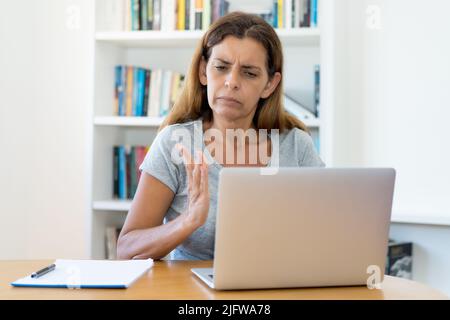 Reife Erwachsene Lehrerin im Gespräch mit Studenten bei Online-Vorlesung am Computer zu Hause oder im Büro Stockfoto