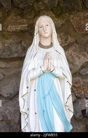 Die Statue unserer Lieben Frau von Lourdes (Notre Dame de Lourdes) in einer Grotte in einem Garten in Valenciennes, Frankreich. Stockfoto