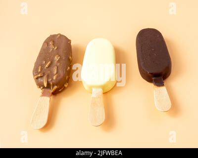 Drei Arten von Eis auf einem Stock. Eis auf orangefarbenem Hintergrund. Stockfoto