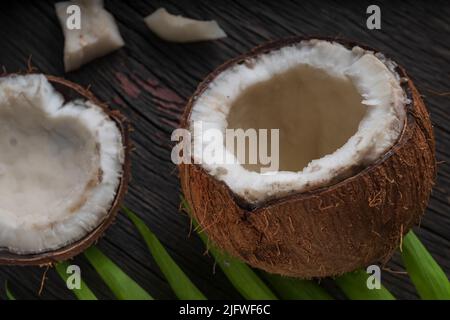 Gehackte Kokosnuss auf einem hölzernen Hintergrund, Draufsicht. Kokosmilch und Kokosflocken sind tropische Lebensmittel Stockfoto