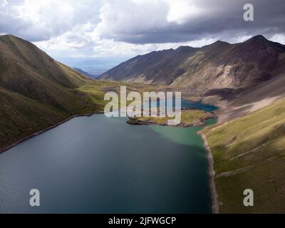 Luftaufnahme des Sees, der von schneebedeckten Berggipfeln in den Tian Shan Bergen Kirgisistans umgeben ist. Stockfoto