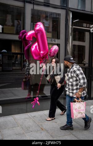 Eine Frau trägt am 5.. Juli 2022 in London, England, 21. Geburtstagsballons in der Oxford Street. Stockfoto