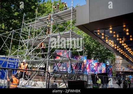 Eine Arbeitsmannschaft bereitet den Bereich des roten Teppichs auf, wo bereits Plakate vorhanden sind, um den neuesten Marvel-Film „Thor: Love and Thunder“ zu vermarken, dessen Premierenveranstaltung heute Abend, am 5.. Juli 2022, in London, England, auf dem Leicester Square gezeigt wird. Stockfoto