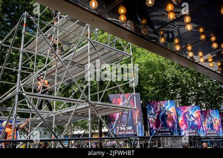 Eine Arbeitsmannschaft bereitet den Bereich des roten Teppichs auf, wo bereits Plakate vorhanden sind, um den neuesten Marvel-Film „Thor: Love and Thunder“ zu vermarken, dessen Premierenveranstaltung heute Abend, am 5.. Juli 2022, in London, England, auf dem Leicester Square gezeigt wird. Stockfoto