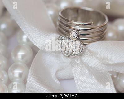 Nahaufnahme der Herzform des Dimond-Ringes auf dem Tisch und mit Perlen und Rippenbund verziert Stockfoto