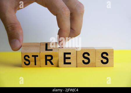 Hand hält Holzwürfel mit Wort WENIGER und STRESS. Speicherplatz kopieren. Stresskonzept für Unternehmen. Stockfoto