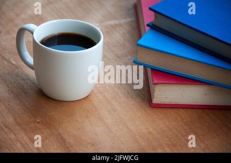 Kaffee mit Büchern auf einem Holzschreibtisch. Direkte Aussicht. Speicherplatz kopieren. Stockfoto