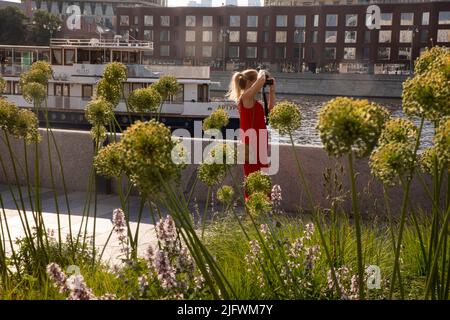 Moskau, Russland. 26.. Juni 2022. Eine junge Frau in einem roten Kleid fotografiert bei heißem Wetter im Zentrum von Moskau, Russland, den Krimdamm im Muzeon Arts Park Stockfoto