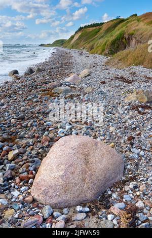 Küste von Kattegat - Helgenaes, Dänemark. Ozeanwellen, die auf leere Strandsteinchen abwaschen. Ruhiges, friedliches Paradies der Sommerseestücke und des Himmels Stockfoto