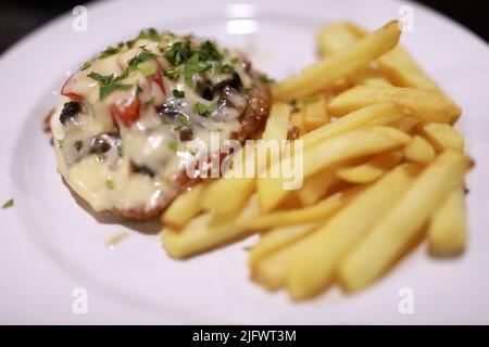 Gebackenes Fleisch mit pommes auf dem Teller im Restaurant Stockfoto