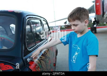 Porträt eines Kindes, das die Tür eines Oldtimers öffnet Stockfoto