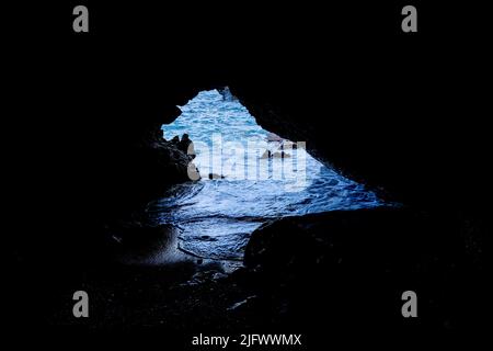 Die Meereshöhle öffnet sich zum Meer am schwarzen Sandstrand im Waianapanapa State Park, Hana, Maui, Hawaii. Stockfoto