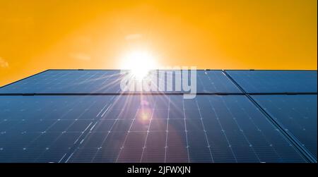 Sonnenkollektoren auf dem Dach vor hellem gelben Himmel Hintergrund. Stockfoto