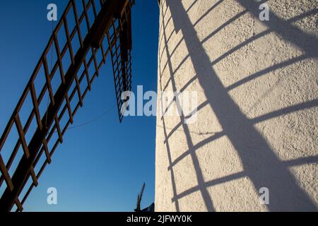 Primer plano de las aspas de un molino de viento y su sombra en el molino, cielo azul, Campo de Criptana, España Stockfoto