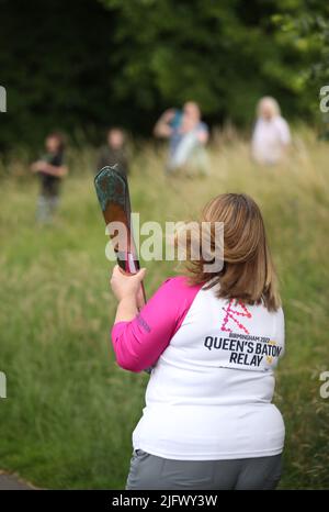 Ein Baton-Träger hält den Baton der Königin während eines Besuchs des Baton-Staffelteams der Commonwealth Games Queen im Pittville Park in Cheltenham, Gloucestershire. Stockfoto