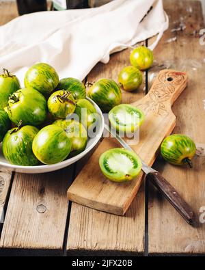 Reife grüne Tomaten auf einem Holztisch, Salat kochen. Stockfoto