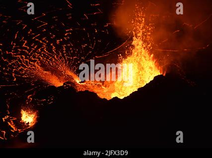 Lavafontänen aus dem westlichen Schlot innerhalb von Halema'uma'U versorgen den Lavasee durch einen kurzen Auslauf mit Lava. Gleichbleibende Brunnenhöhen von 10Ð15 Metern (30Ð50 ft), unterbrochen durch häufige größere Spritzerbüsten, die die Höhe des Kegels (30 m oder 100 ft) überschreiten. Hawaii, USA Oktober (12) 2021 Ausbruch. Kredit: B.Carr/USGS Stockfoto