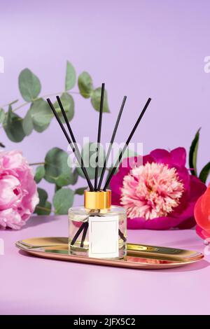 Wohnkomfort, Dekoration und Aromatherapie-Konzept. Duftender Diffusor auf dem goldenen Teller. Kreatives Bild von Glasdiffusorflasche und Diffusorsticks Stockfoto