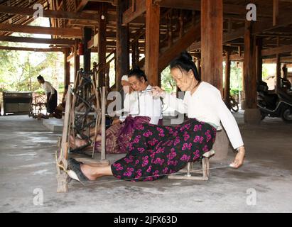 Yunnan, China - 01. Dezember 2010: Die thailändischen ethnischen Frauen weben Baumwollfäden auf Vintage-Holzwebmaschine in der Provinz Yunnan, China Stockfoto