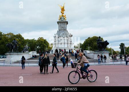 Frau auf dem Fahrrad. Das Victoria Memorial ist ein Denkmal für Queen Victoria, das am Ende der Mall in London liegt und vom sc entworfen und ausgeführt wurde Stockfoto