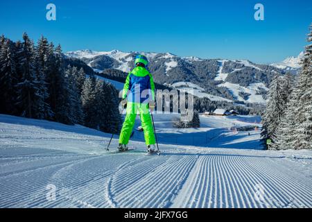 Rückansicht eines Jungen Alpin Ski Abfahrt auf der frischen Piste Stockfoto