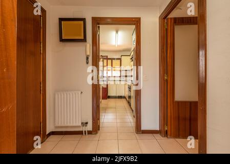 Eingangshalle und Verteiler eines Hauses mit cremefarbenen Keramikböden, Holzschreinerei aus rotem Holz und Eingang zu mehreren Räumen Stockfoto