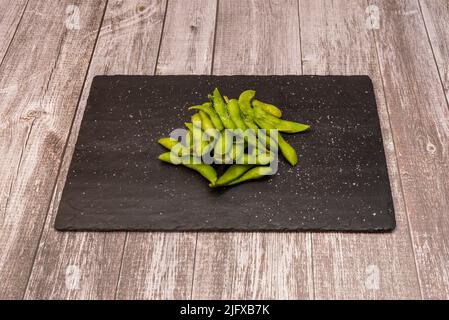 Edamame ist der japanische Name für eine kulinarische Zubereitung unreifer Sojabohnenschoten, die in Salzwasser gekocht und ganz serviert werden Stockfoto