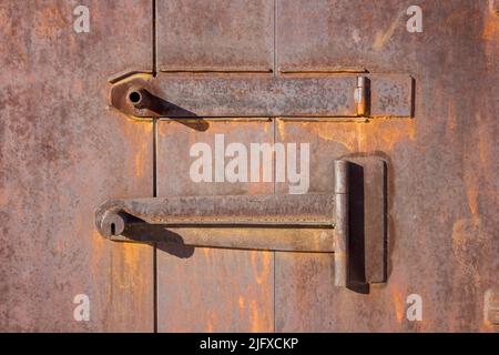Nahaufnahme des rostigen Metallgaragentor. Altes Garagentor mit Vorhängeschloss als Hintergrund. Stockfoto